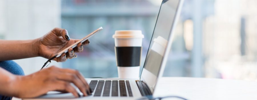 person using smartphone and MacBook